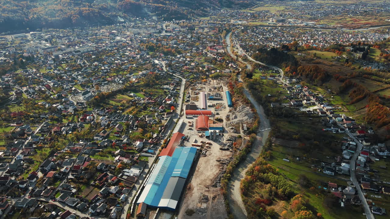 Aerial drone view of Viseu de Sus, Romania. A lot of residential buildings, railway station, river, hills covered with yellowing forest