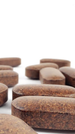 close-up of scattered brown nutritional supplements on white background