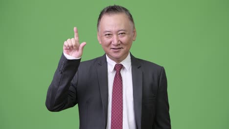 mature happy japanese businessman pointing finger up