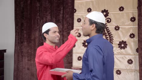 indian muslim man offering sweets to his friend on eid festival