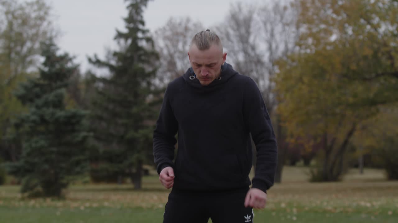 초록색 나무와 풀이 있는 공원에서 서 있는 남자 권투 선수 가 따뜻 해지고 있다