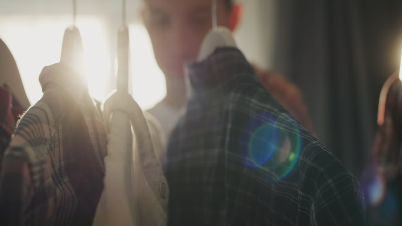 한 젊은이 가 옷장 에 서서 자기 를 위해 셔츠 를 선택 한다