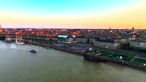 Place-de-la-Bourse-and-the-Garonne-river-during-Wine-Fair-with-sailboats-and-galleon-in-Bordeaux-France,-Aerial-pan-left-approach-shot