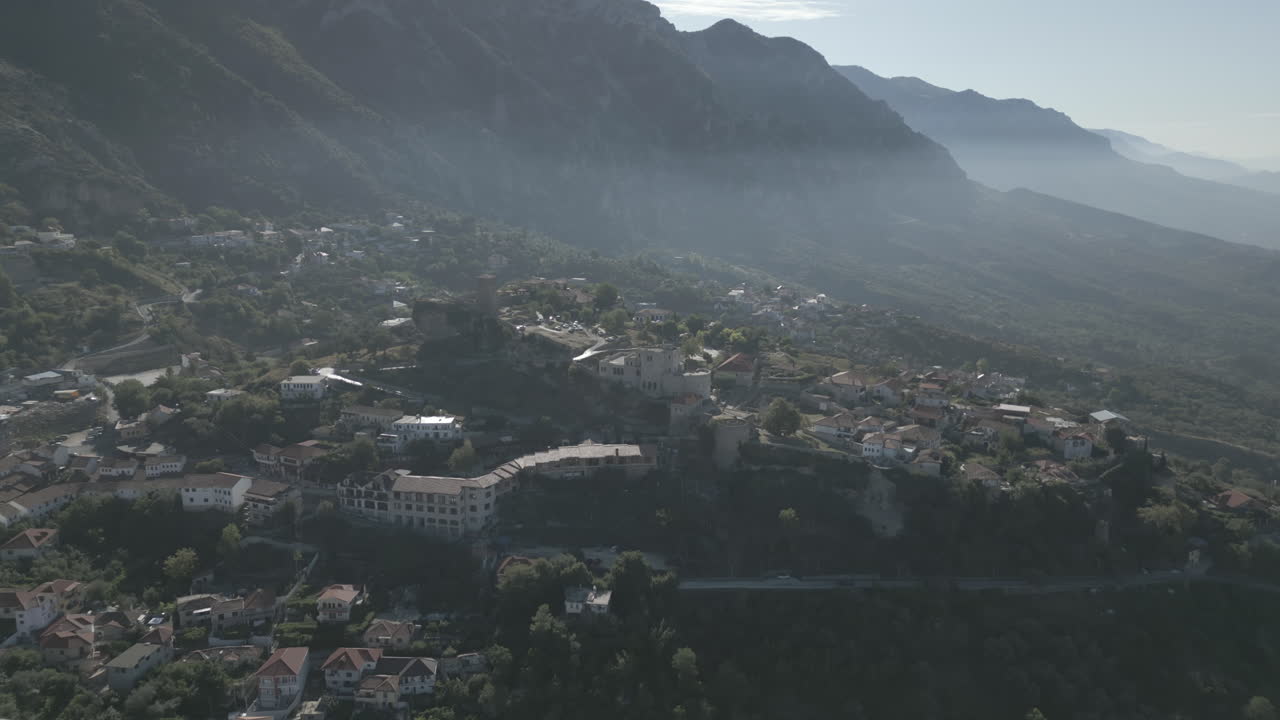 droneshot desde arriba kruje albania volando sobre el castillo en el acantilado en un día nublado con nubes contra las montañas registro