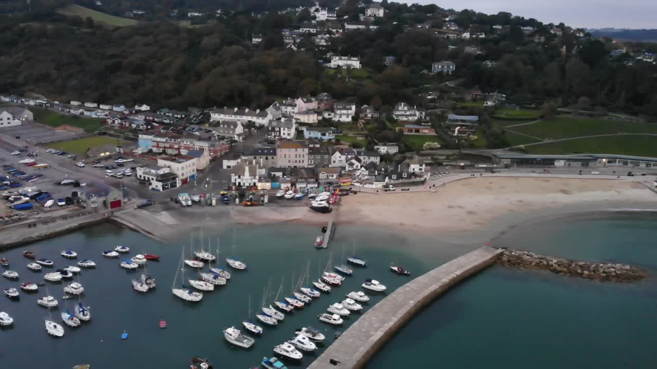 Aerial panning left shot of Lyme Regis town and the Cobb South west England at dawn