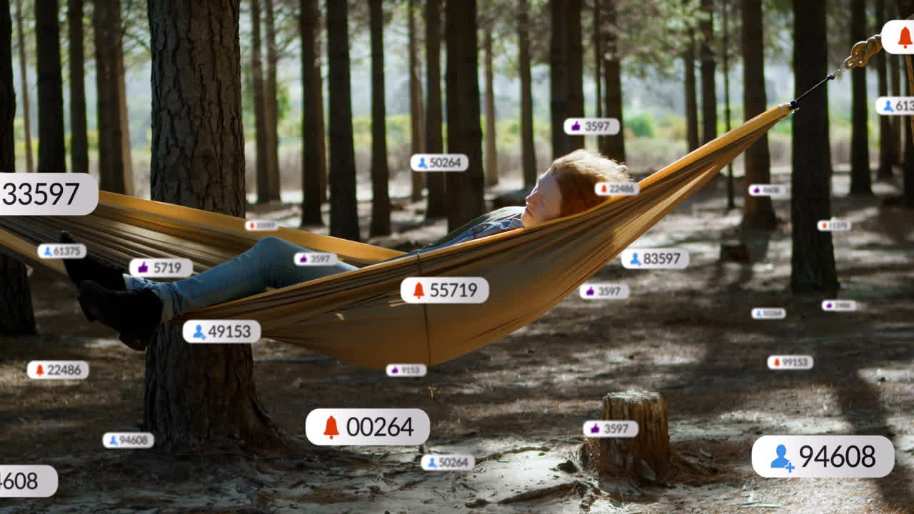Relaxing in hammock among trees, person viewing animation of social media notifications