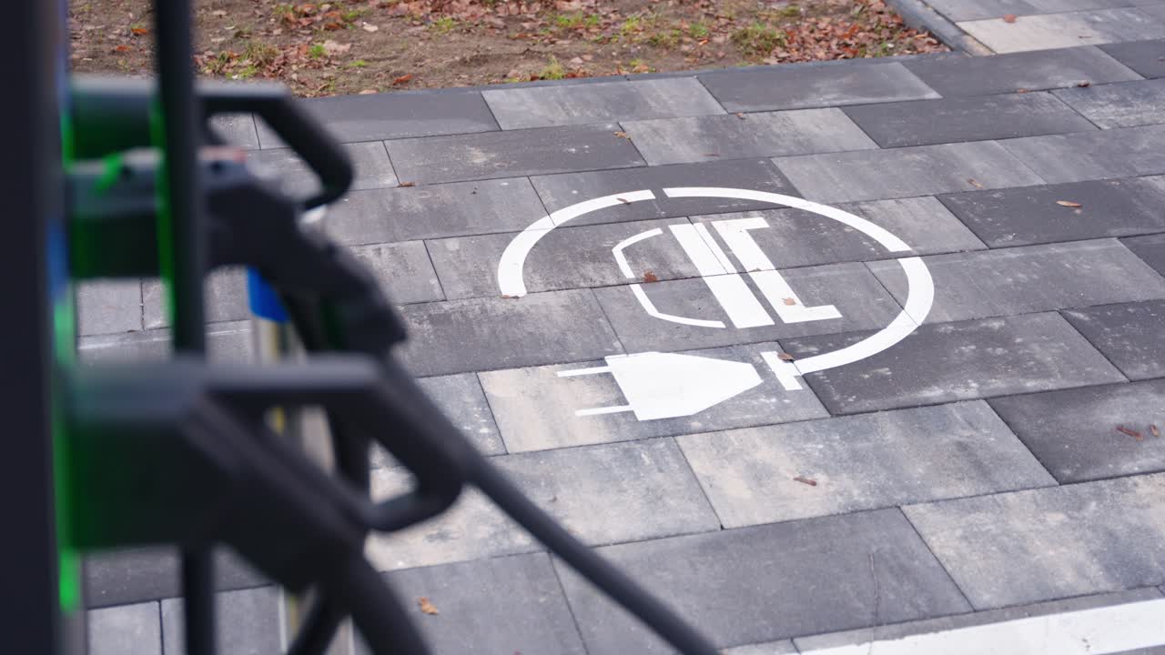 Reveal past plugs of electric vehicle charging point markings and charging cable on pavement