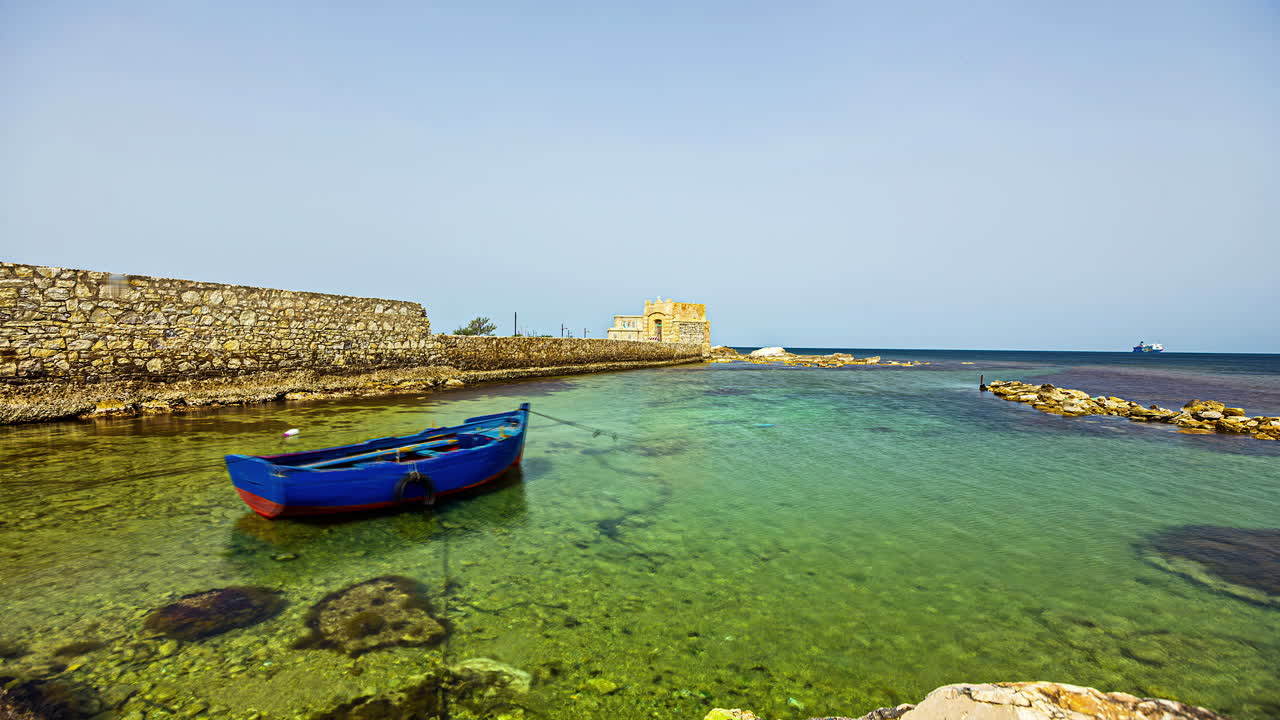 vista estática de una casa antigua a lo largo de la playa del increíble pueblo costero de la isla de sicilia, provincia de trapani, italia durante el día en timelapse