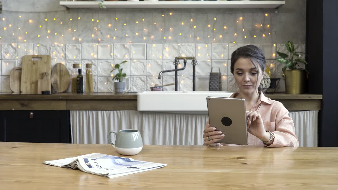 mujer leyendo en una tableta en una cocina acogedora