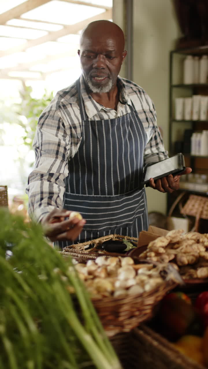 Slow-motion vertical video of elderly Black shopkeeper inventorying food shop