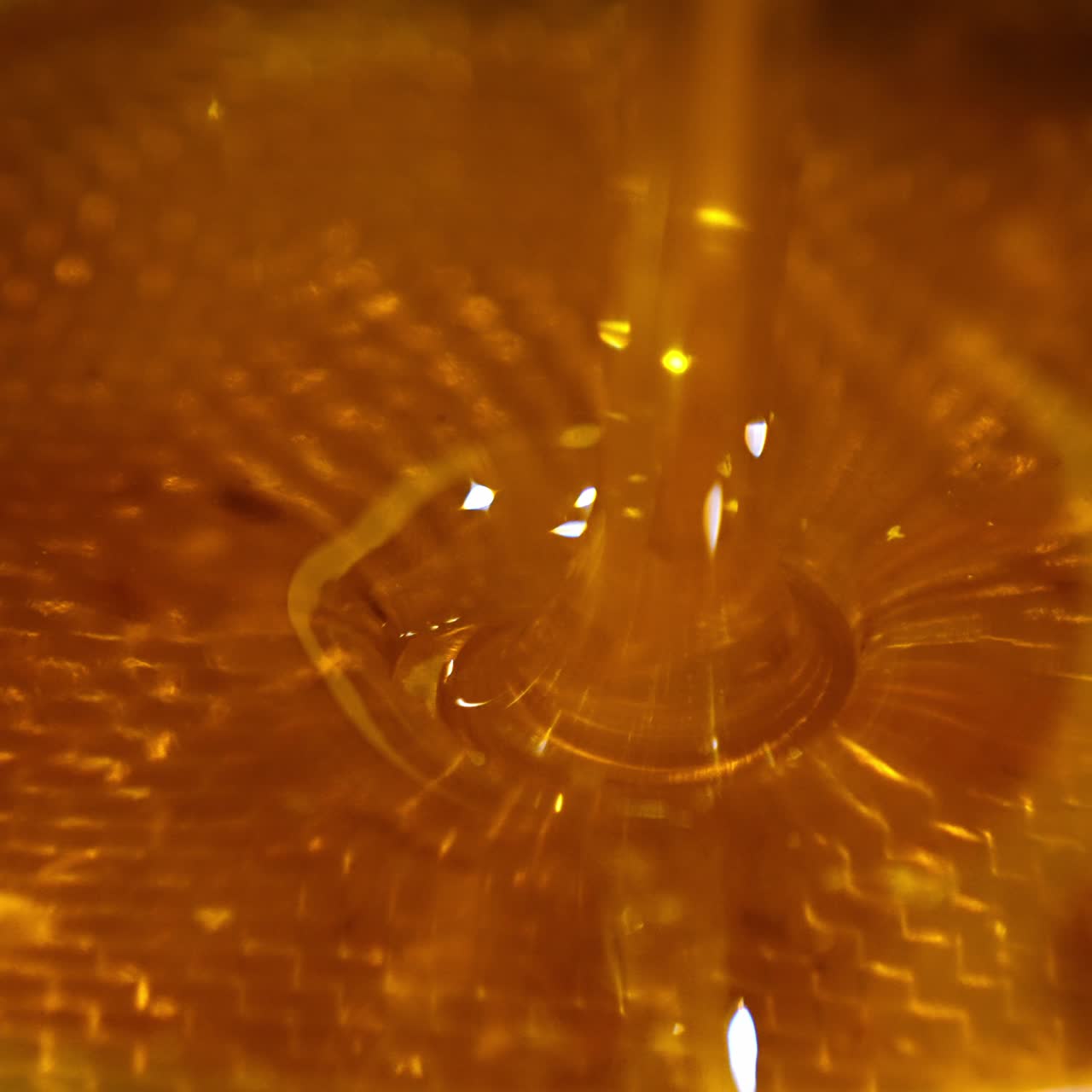 Beautiful fresh healthy organic honey flowing on the sieve. Liquid just extracted honey being filtered from wax particles