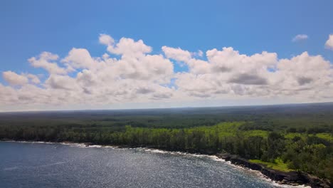 Fesselnde-Luftaufnahme-Eines-üppigen-Regenwaldes,-Der-Auf-Einen-Unberührten-Strand-Trifft,-Mit-Flauschigen-Wolken,-Die-Die-Skyline-Von-Big-Island,-Hawaii,-Schmücken