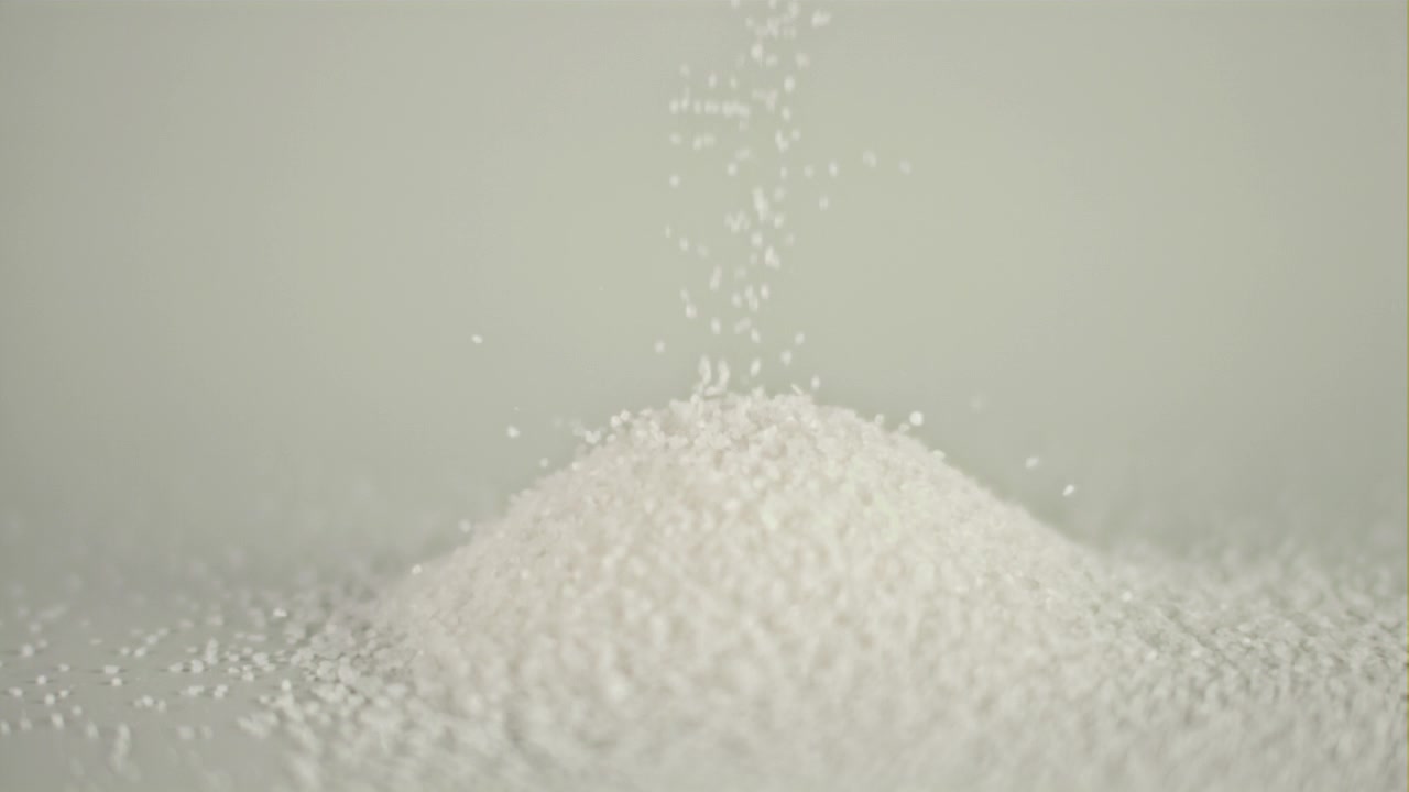 Zucchero bianco o sale che cade e forma un mucchio