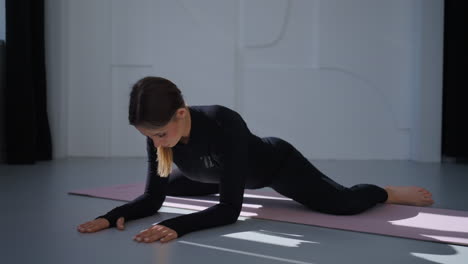 mujer haciendo ejercicio de estiramiento de yoga en una alfombra rosa