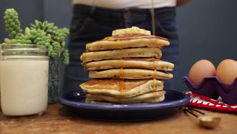 Close-up-shot-of-syrup-being-poured-over-fluffy-pancakes-that-are-placed-in-a-purple-plate