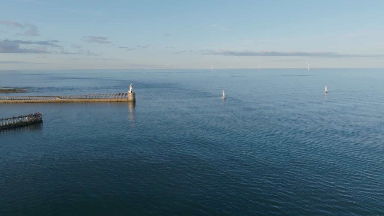 Two yachts sailing calm blue sea close to white lighthouse