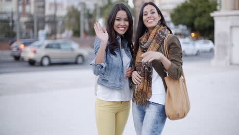 Happy-young-women-waving-at-the-camera