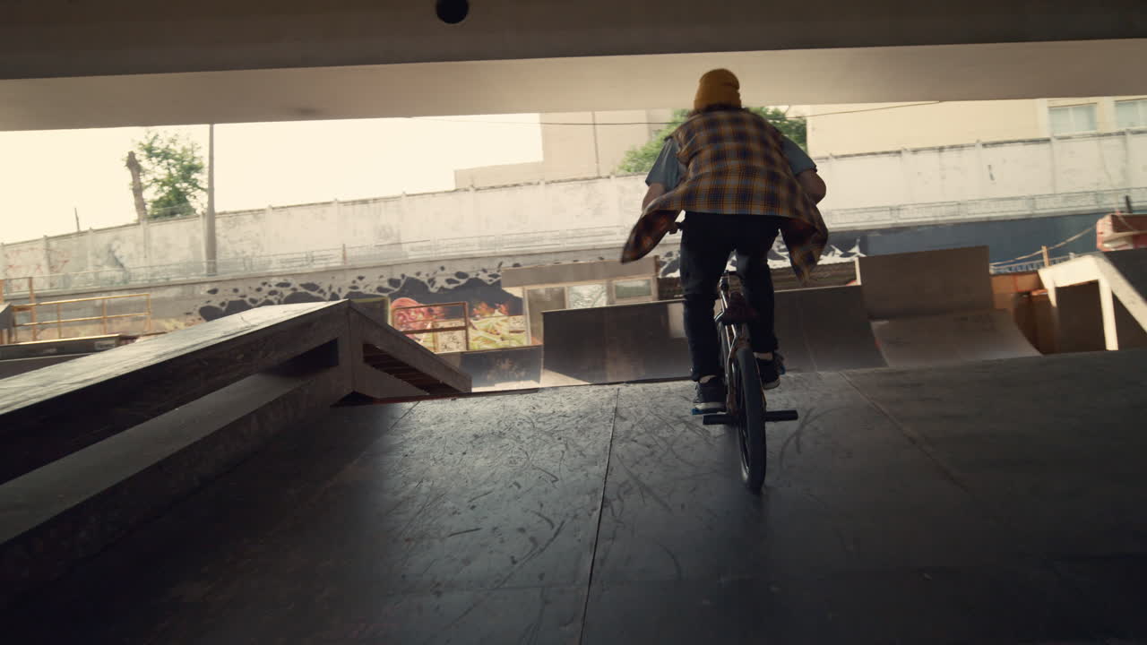 Młody rowerzysta wykonujący kaskaderską sztuczkę na poręczy w miejskim skateparku. Rowerzysta pędzący na BMX-ie.