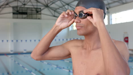 joven biracial ajusta sus gafas de natación en la piscina