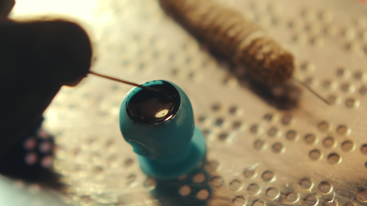Hand of Tattoo Artist Dipping Needle in Black Ink