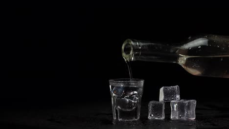 vertiendo vodka en un vaso con hielo