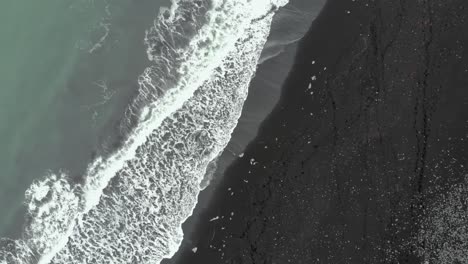 Zoom-out-top-down-of-Diamond-Beach-in-Iceland,-black-beach-with-ice