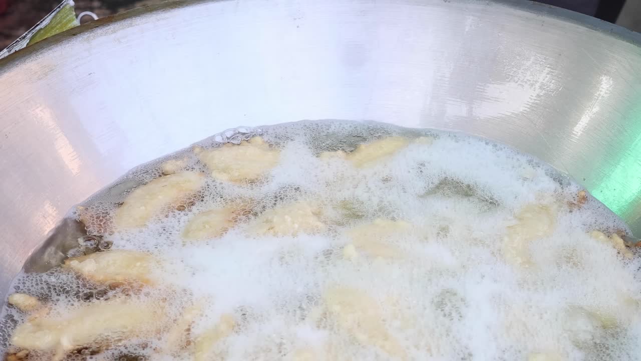 plátanos en rebanadas fritos en aceite caliente en una sartén.