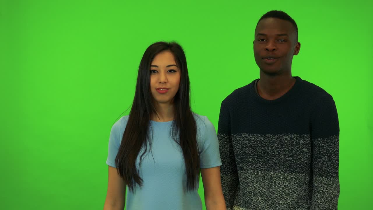 una joven asiática y un joven negro protestan ante la cámara - estudio de pantalla verde