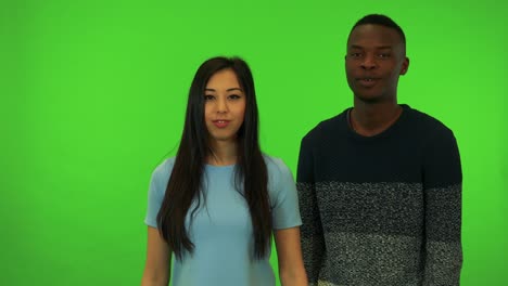 a young asian woman and a young black man protest to the camera - green screen studio