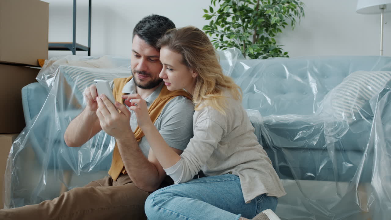 Coppia che guarda lo smartphone durante il trasloco