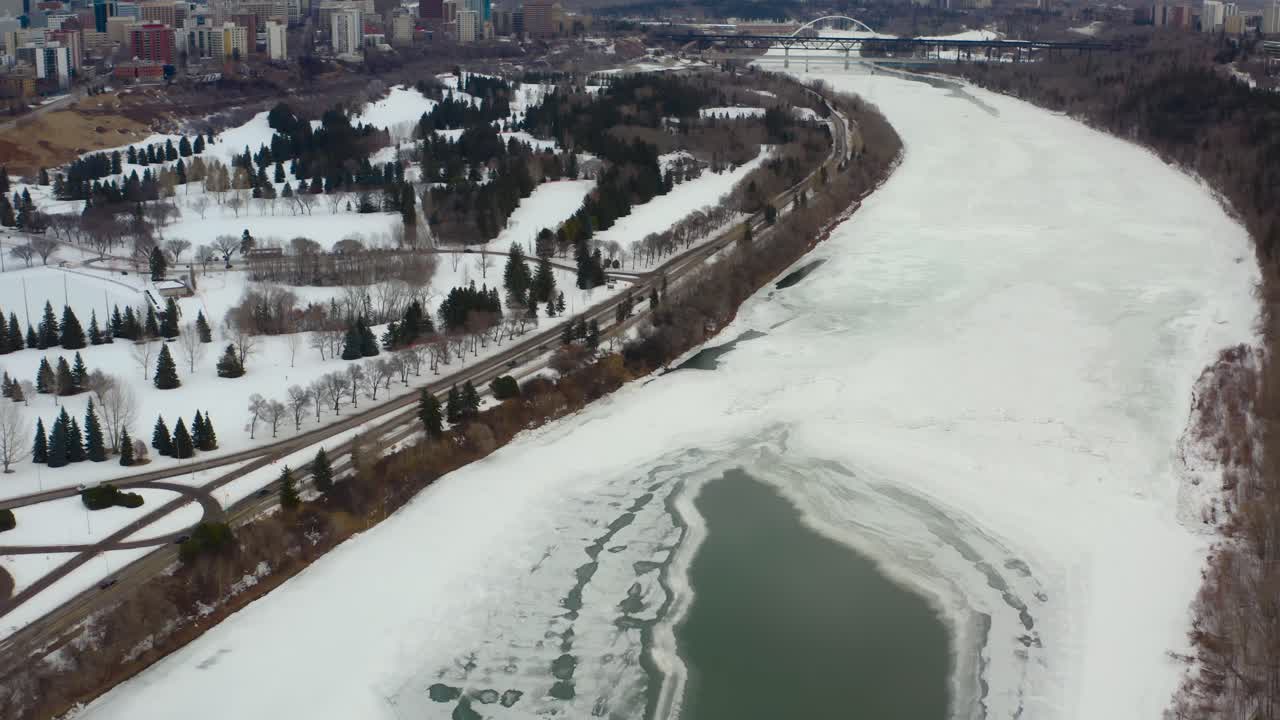 vista aérea de pájaro volar sobre el puente groat rd nw cubierto de nieve helado río saskatchewan norte en una tarde sombría de invierno rodeado de tranquilos campos de golf y el parque victoria a la izquierda alberta 4-7