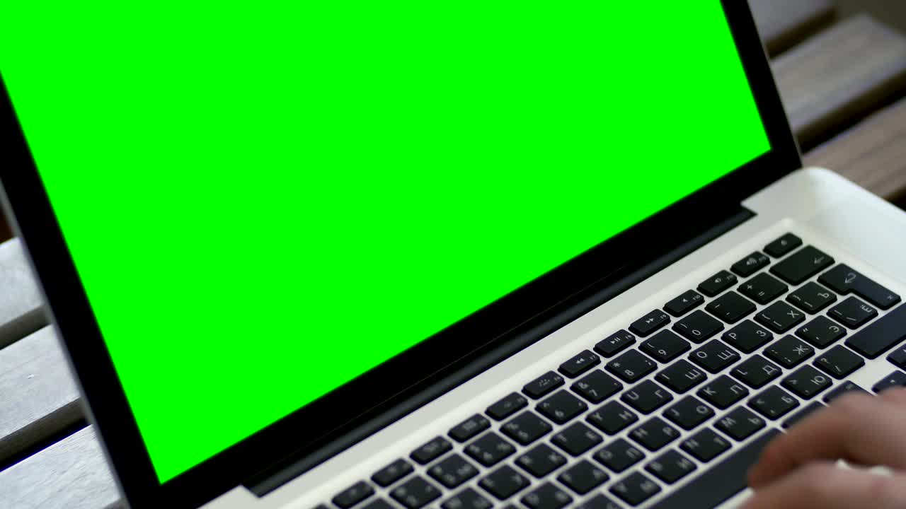 mano de un hombre trabajando en una computadora portátil escribiendo en el teclado. pantalla verde de cerca