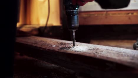 persona que perfora un agujero en tablas de madera utilizando un taladro eléctrico