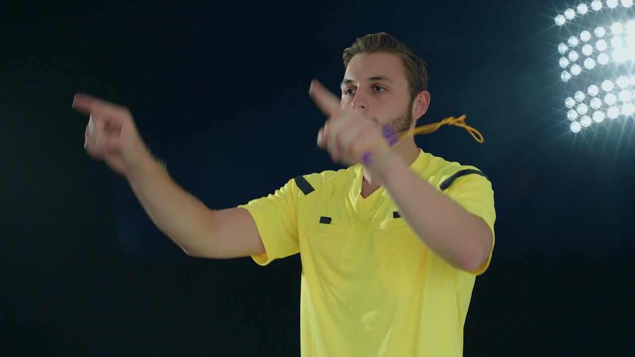 검은색 배경의 축구 심판이 휘파람을 치고 비디오 보조 심판을 보여줍니다.