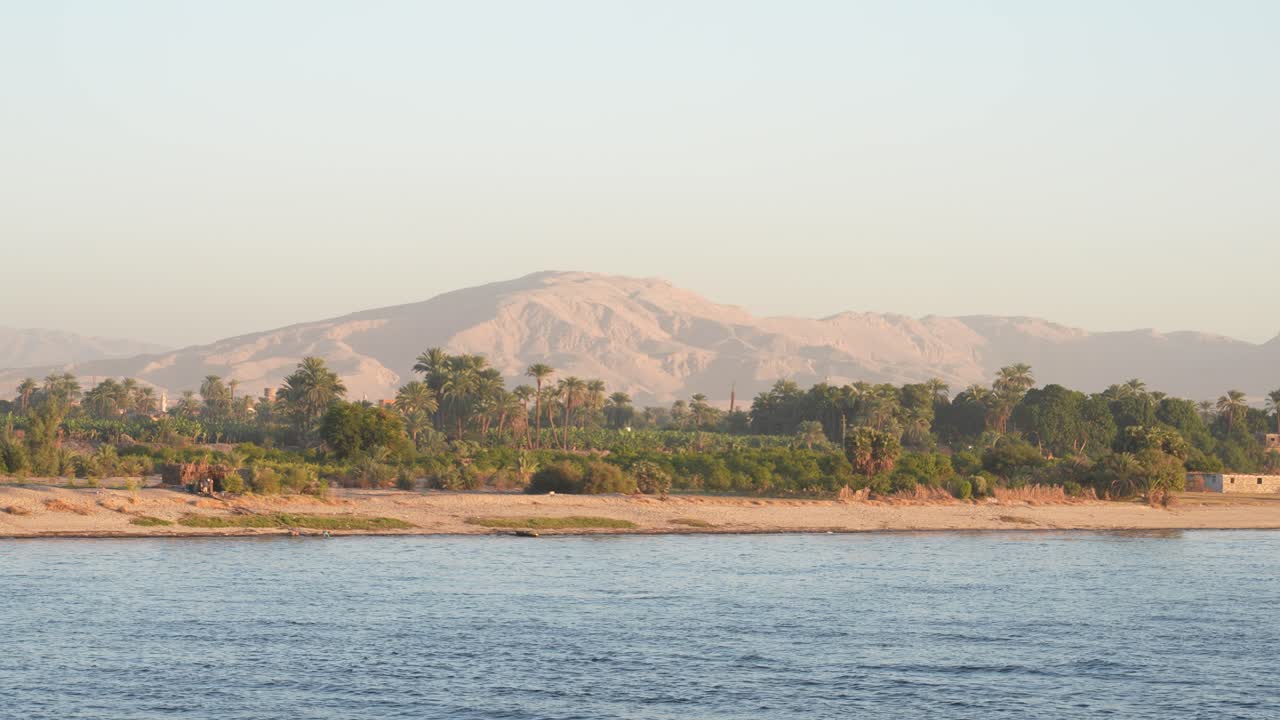 Telephoto sailing Nile River and farms in the foreground distant mountain range in the background Egypt