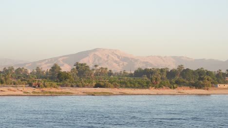 telephoto sailing nile river and farms in the foreground distant mountain range in the background egypt