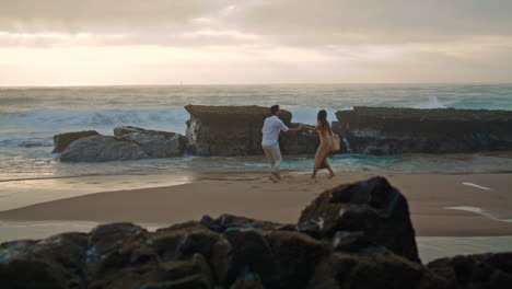 joyful people spinning sea beach vacation. unknown couple having fun vertically