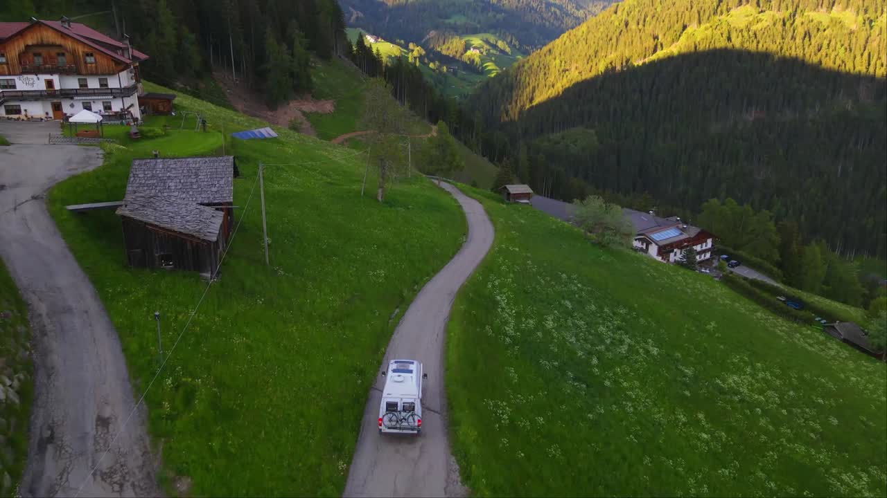 furgoneta blanca a través de un sinuoso camino de montaña alrededor de los alpes - vista de arriba del avión no tripulado en toblach, italia
