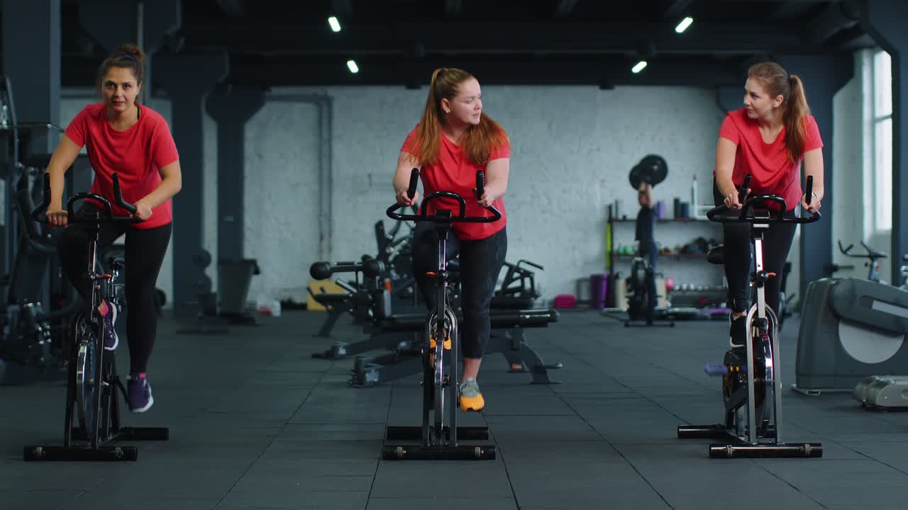 체육관 에서 자전거 를 타고 에어로빅 라이딩 훈련 을 하는 단체 운동 여자 들