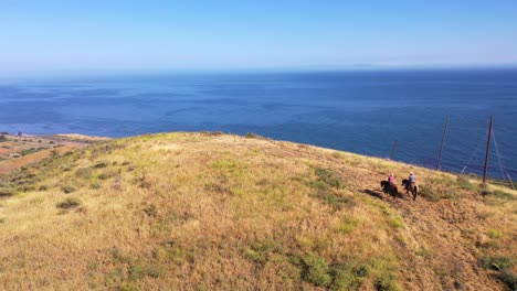 beautiful aerial of retired retirement couple riding horses horseback on a ranch overlooking the pacific ocean in santa barbara california 1