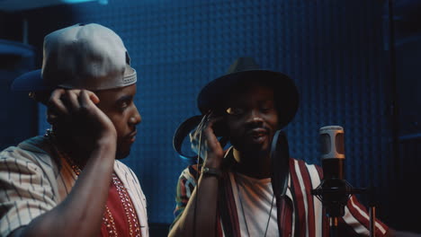 young attractive stylish blues male singers singing a duet in the microphone while recording a song in the studio