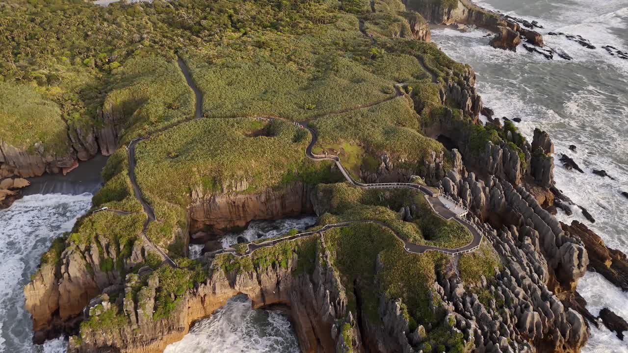 Naturskön gångväg som slingrar sig över Pancake Rocks-formationerna med Tasmanhavet som slår mot klipporna nedanför i Punakaiki, Nya Zeeland. Flygfoto med drönare.