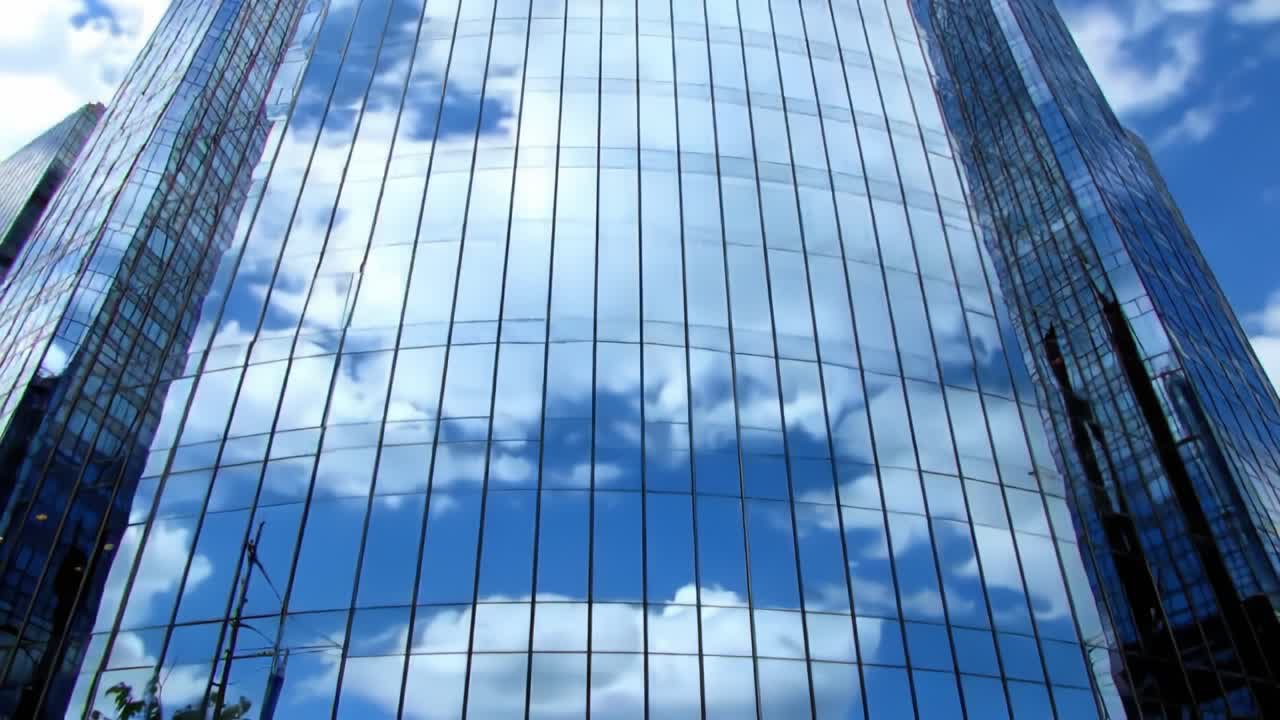 Reflections of Cloudy Skies on Modern Glass Facade of a Skyscraper, Capturing the Beauty of Urban Architecture Against a Blue Sky