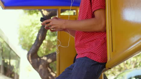 viajero masculino usando teléfono móvil en la parada de autobús 4k
