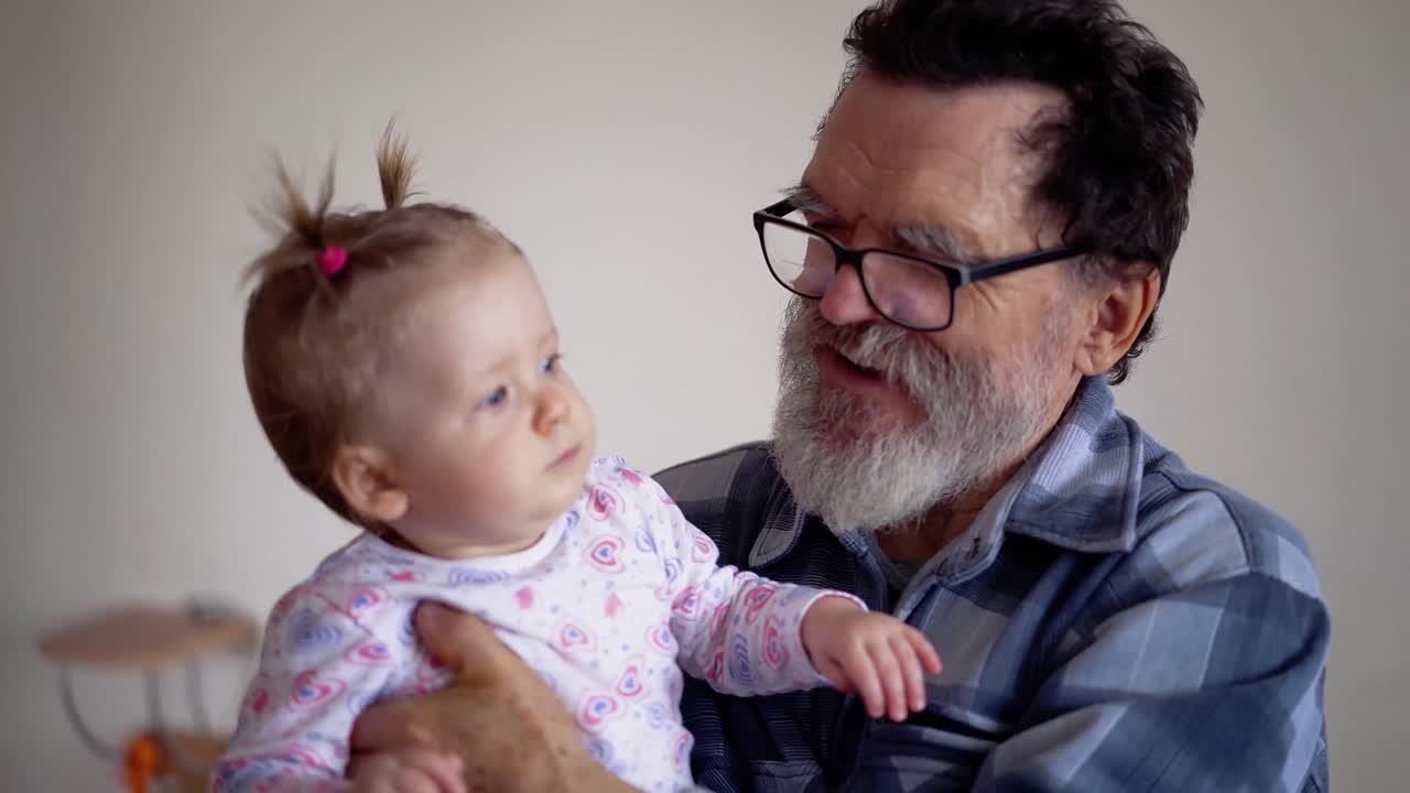 Abuelo con barba y gafas jugando con una nieta pequeña y adorable 1