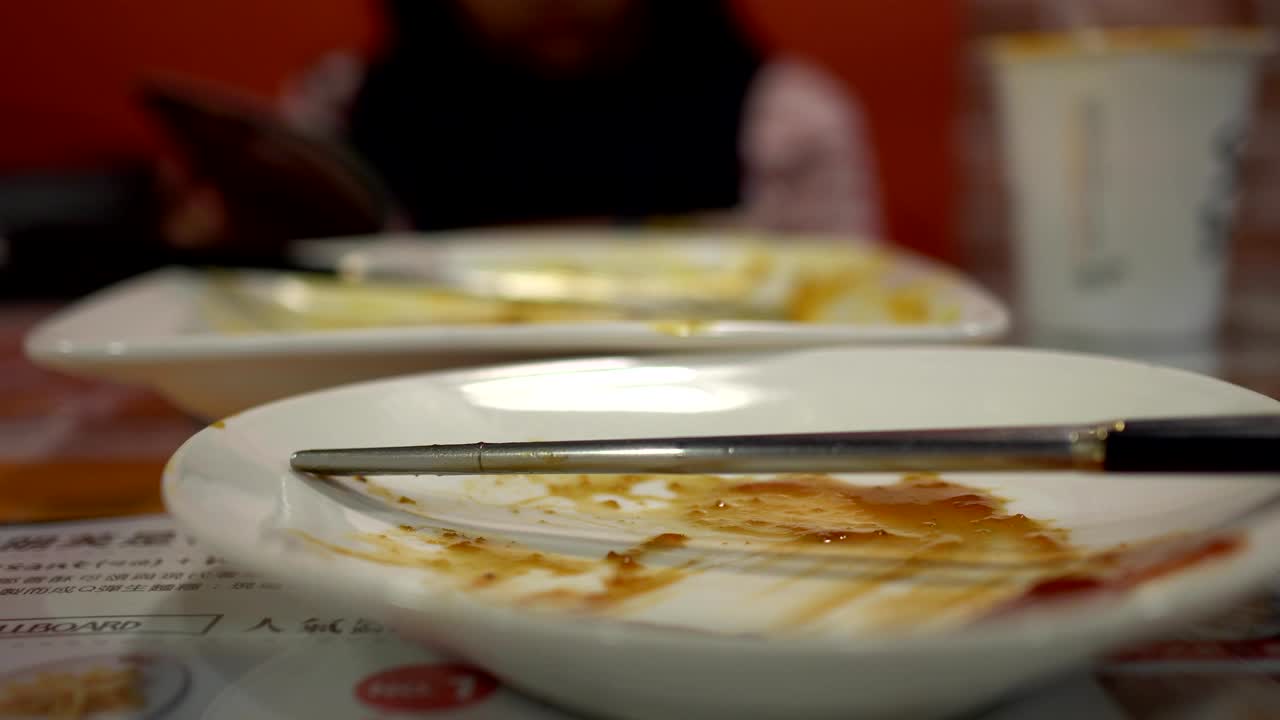 식당에서 음식을 먹은 후 빈 접시. 가락과 함께. 흐릿한 배경은 식사를하는 작은 소녀입니다.