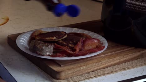 african american middle aged female hand pouring syrup on pancakes