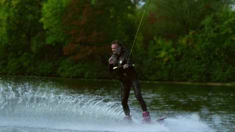 man wakeboarder making signs by hands during movement on river behind boat