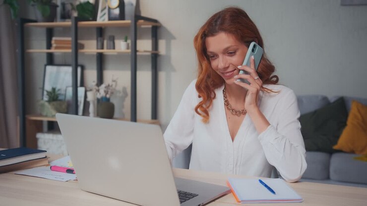 Manager donna lavora in modalità multitasking, parlando al telefono e digitando al portatile.