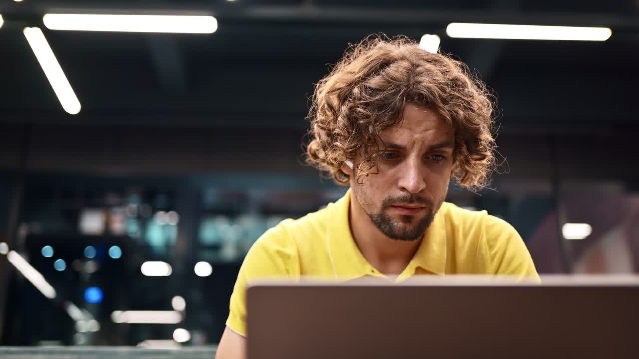 Man in yellow shirt standing on a couch and writing in a notebook